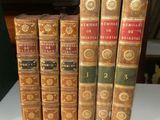 Plusieurs vieux livres sont alignés sur une table devant une horloge