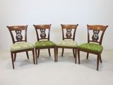 four chairs with green upholstered cushions and a wooden frame