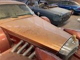 a rusted car in a junkyard with other cars in the background