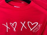 two red t - shirts with the words xx and x on them hanging on a rack