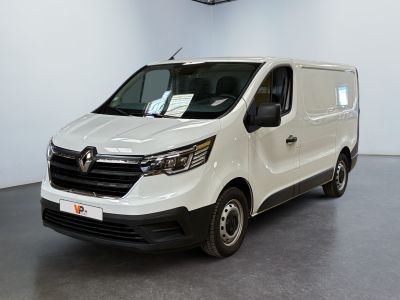 La camionnette blanche est garée dans une grande pièce au sol noir.