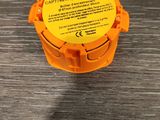 un récipient en plastique orange muni d'une étiquette jaune, posé sur une surface métallique