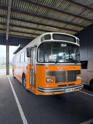 un bus orange et blanc garé sur un parking à côté d'une camionnette blanche