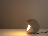 a white lamp on a white table next to a wall