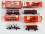 six types différents de petits trains miniatures posés sur une surface blanche