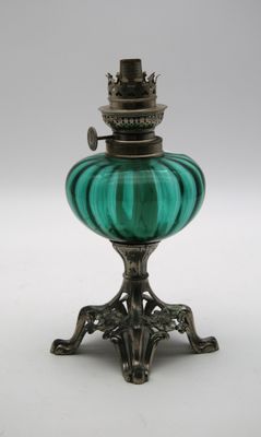 une lampe à huile en verre vert posée sur un support muni d'un socle en métal