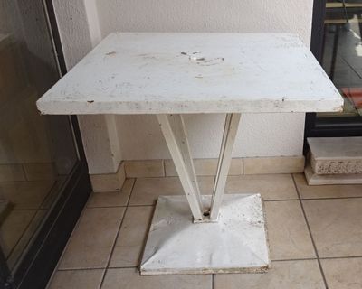 une petite table blanche posée sur un sol carrelé, près d'une fenêtre