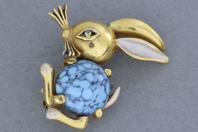 une image représentant une broche en forme de lapin avec une pierre bleue dans la gueule