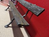 a wooden bench sitting next to a red wall