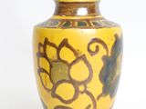 a yellow vase with a black and brown design on it