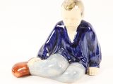 a figurine of a boy sitting on the ground
