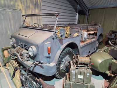 an old military vehicle parked in a garage next to other military vehicles