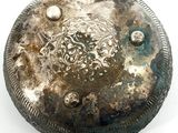 a silver plate with a design on it on a white surface