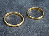 two gold wedding rings on a black surface