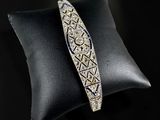 a close up of a silver bracelet on a black pillow