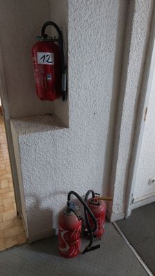 un extincteur fixé au mur à côté d'une borne d'incendie