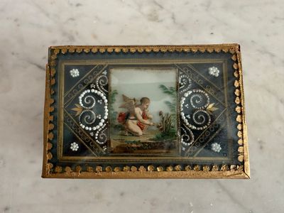 a small box with a painting on it on a marble surface