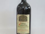 an old bottle of red wine sitting on top of a white table
