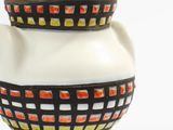 a white vase with a black and orange design on it