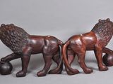 pair of carved wooden lions with ball on grey background