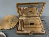 a gold plated case with a mirror and a brush
