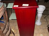 une armoire rouge posée par terre à côté d'une chaise