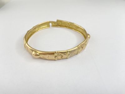 a close up of a gold bracelet on a white surface