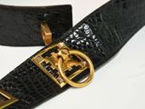 black leather belt with gold buckle on white surface