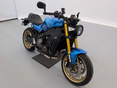 une moto bleue garée dans une pièce aux murs blancs