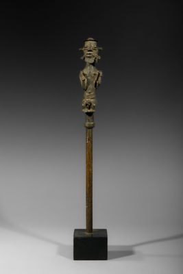 une statue en bronze représentant une femme, fixée sur un poteau en bois
