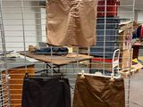 several pairs of pants hanging on a wire rack in a clothing store