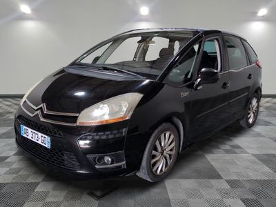 La petite voiture noire est garée dans le garage, sur le sol à damier.