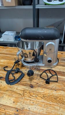 a silver mixer on a wooden table in a kitchen