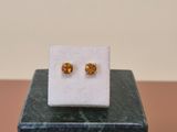 a pair of earrings sitting on top of a marble block