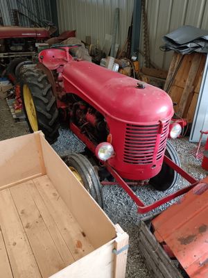 a red tractor parked in a garage next to a crate
