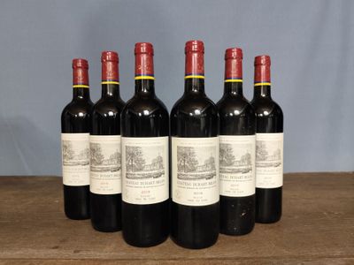 six bottles of red wine are lined up on a wooden table