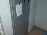 a refrigerator in the corner of a bathroom with a sign on the door
