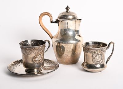 un service à thé en argent composé d'une tasse et d'une soucoupe posées sur une assiette