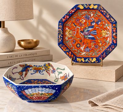 un bol orange et bleu posé sur une table, à côté d'une lampe