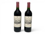 two bottles of red wine sitting next to each other on a white surface