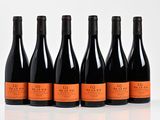 six bottles of wine are lined up in a row on a white surface
