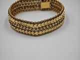 un bracelet composé de perles dorées et noires sur fond blanc