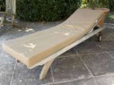 a chaise lounger sitting on a patio with a table and chairs in the background