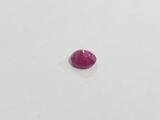 a single ruby stone sitting on top of a white surface