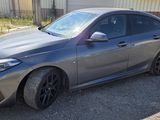 the car is parked on the gravel in front of a building