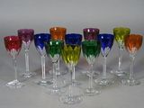 sept verres à vin contenant des liquides de différentes couleurs, posés sur une table