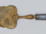 a metal shovel with a handle on a white surface