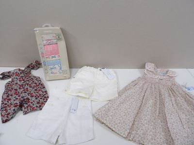 a white table topped with baby clothes and a picture frame