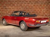a red convertible car parked in front of a brick wall