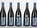 quatre bouteilles de vin sont alignées sur une surface blanche